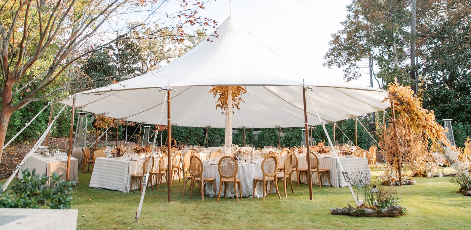 White sailcloth pole tent set for a fall wedding reception surrounded by autumn foliage in Atlanta