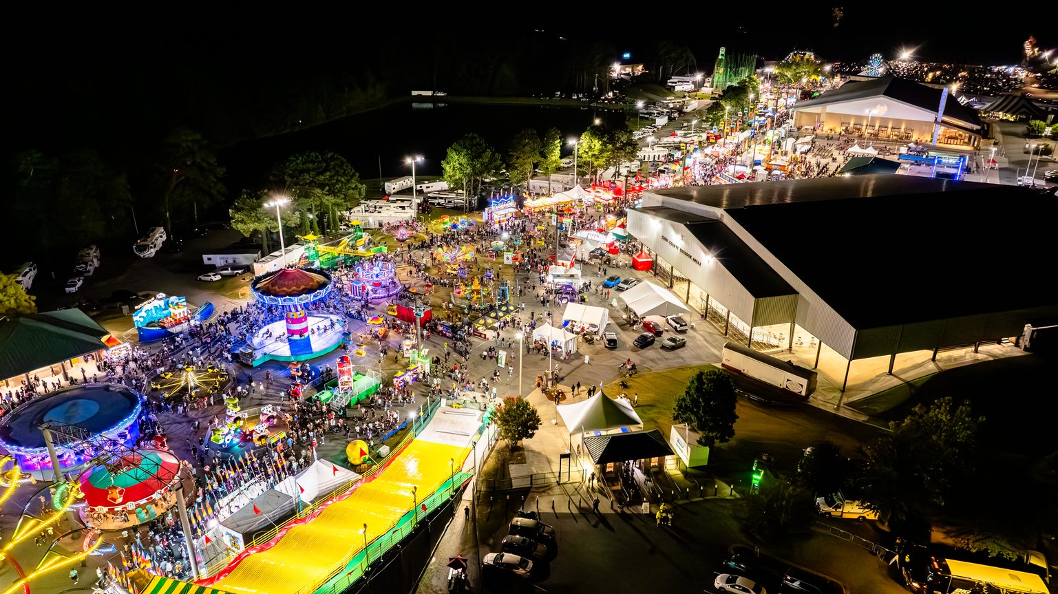 Aerial night view of a fall festival with vendor tents and midway rides in metro Atlanta
