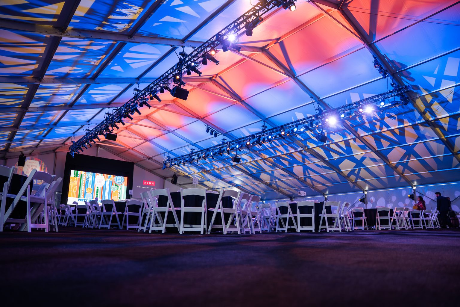 Structure tent interior with truss lighting, stage and screen set for an Atlanta corporate event
