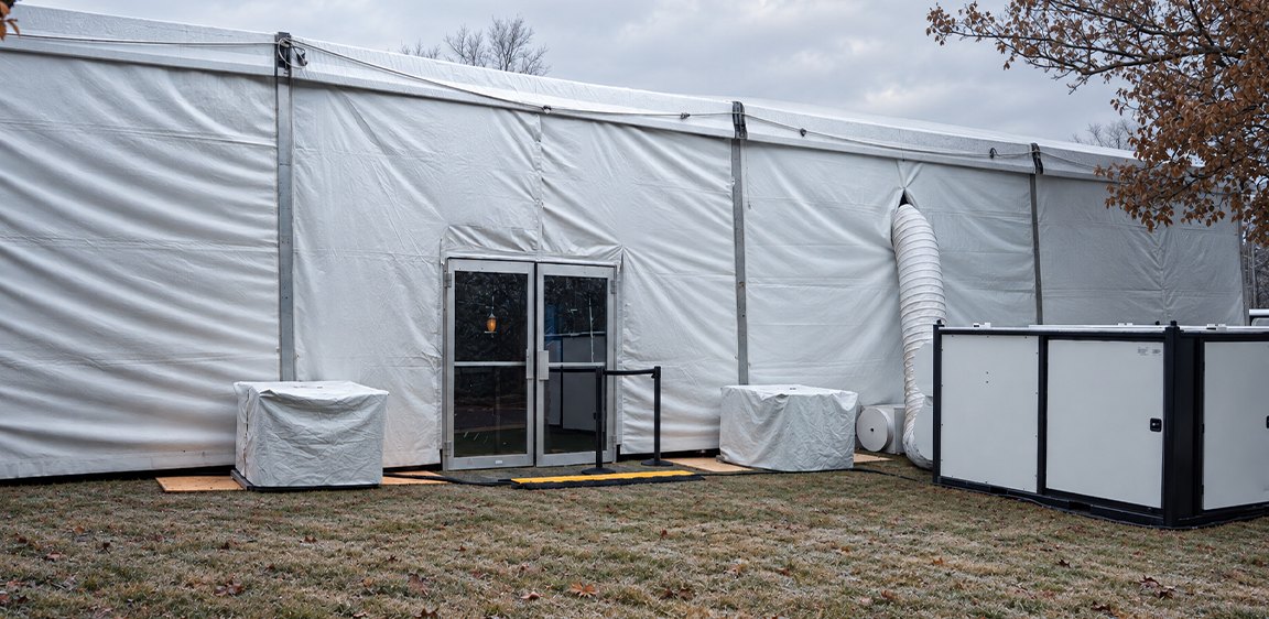 White structure tent with solid sidewalls and HVAC climate control units for a winter event