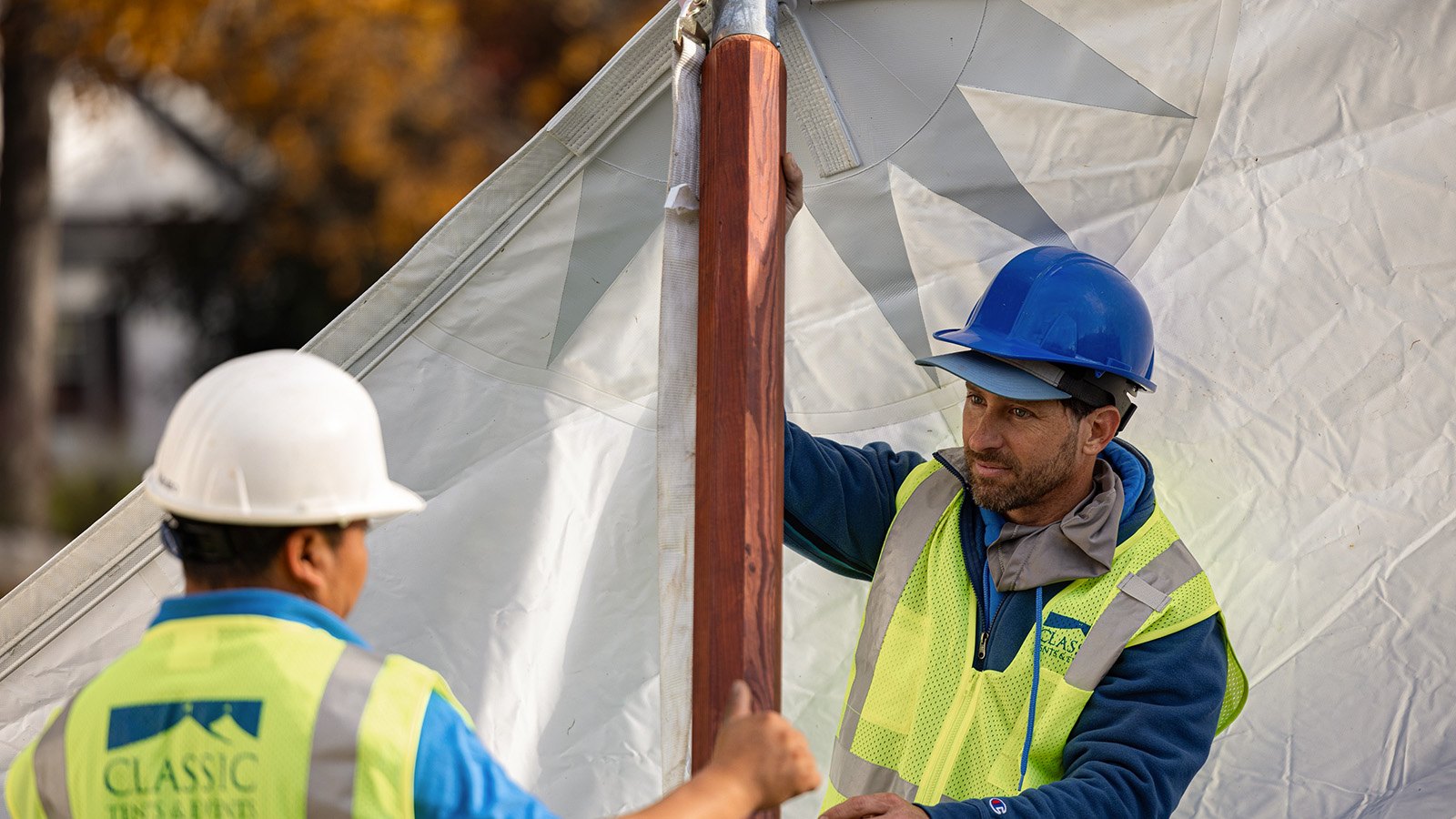 Classic Tents crew in hard hats and safety vests raising a tent pole during installation