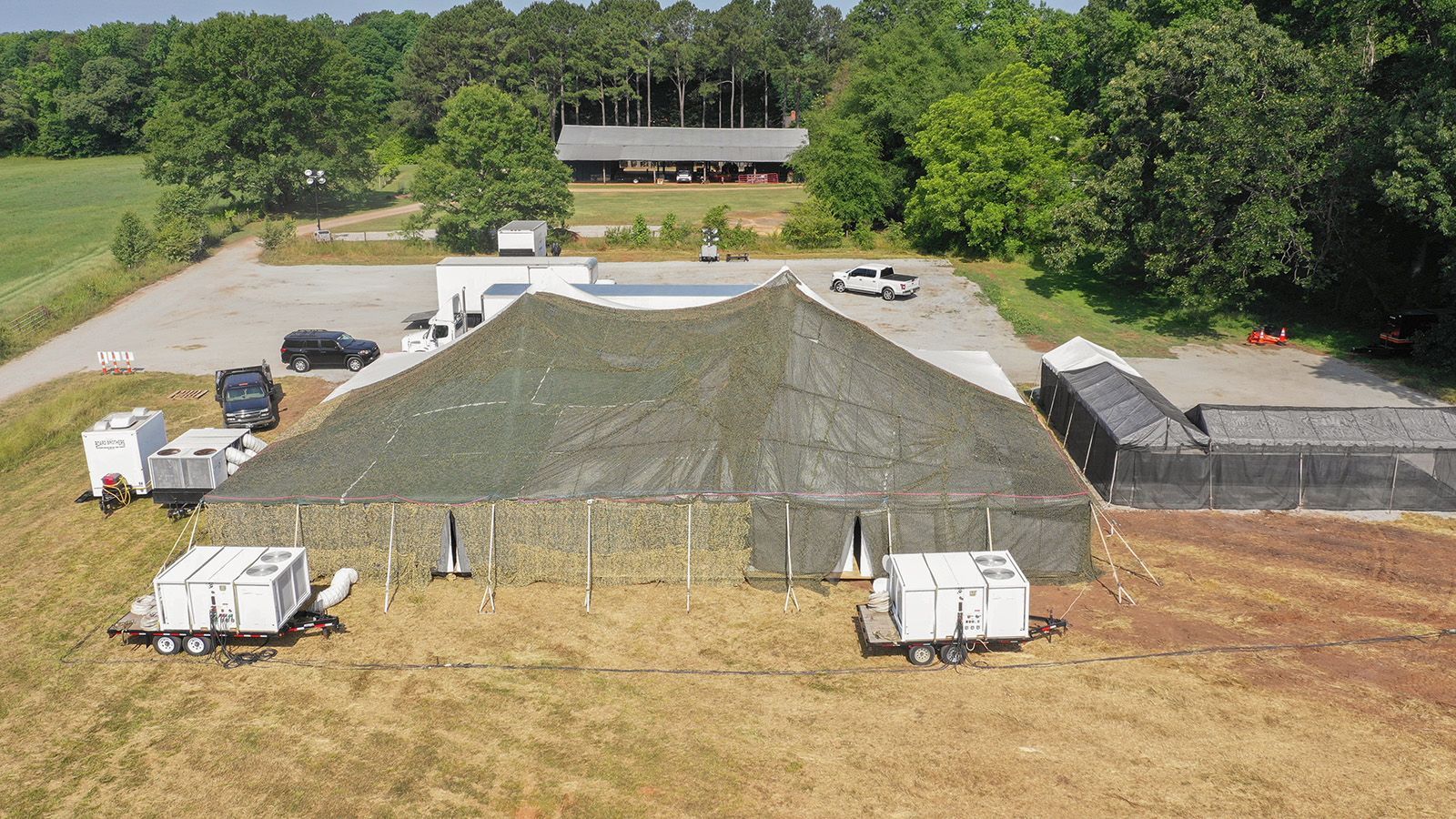 Aerial view of a temporary jobsite tent with trailer-mounted HVAC units and ducting